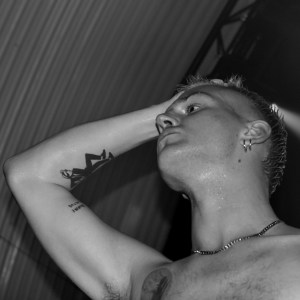 Black & white shot of Hamish, vocalist with VLURE, on stage looking across the crowd, hands on head